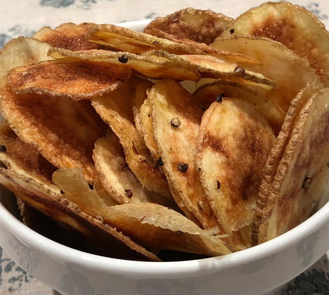 Black pepper potato chips! I don’t know about you but all of this holiday cheer has me looking for ways to lighten things up a bit- these chips aren’t fried- they cook until perfectly crisp in the microwave-and, although a little harder than those that are deep-fried, they’re amazing! Do this: One Idaho potato, scrubbed, dried and sliced very thin (the largest setting on an inexpensive, hand-held mandoline-check out the one I like best on my site). Line the slices up on a large doubled sheet of paper towels and cover with the same, pressing down to dry the slices. Take all the slices and put in a bowl and add enough extra virgin olive oil (or better yet, garlic confit oil) and, if desired, freshly cracked black pepper. Rub the slices, so each one is coated with oil. In batches (how many batches will depend on the size of your microwave) lay the slices, in a single layer, on a sheet of parchment paper that sits on a microwaveable plate. Microwave on high power for 4 1/2 to 5 minutes- or longer, depending on your appliance. Check every 30 seconds, after hitting the 4 1/2 min mark. The slices should be light golden with some spots that are more deeply colored. Place the cooked slices on a large wire rack, where they will crisp up quickly. Continue with the remaining potatoes- adding them to the rack. (You can use the same parchment but use two plates, so the plate can cool down after each batch. Season with kosher salt- Eat